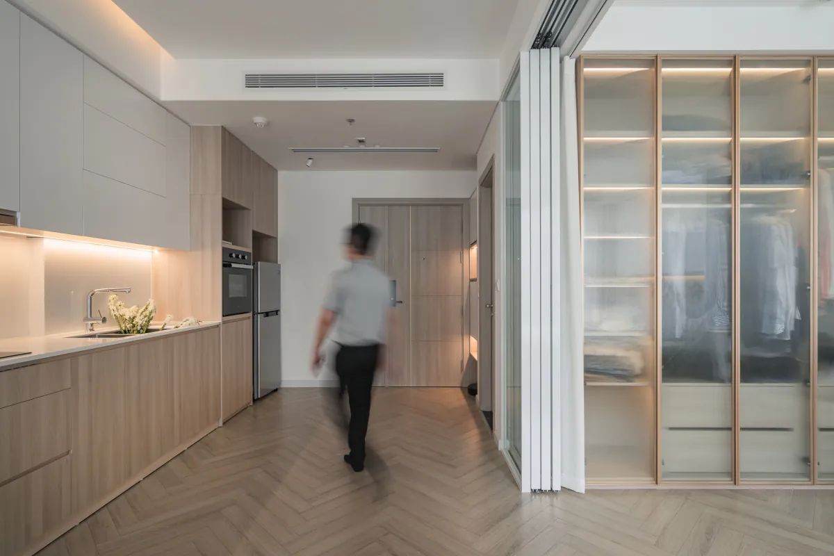 Cửa ra vào dẫn thẳng đến không gian sinh hoạt chung, gồm phòng bếp - khách - ăn. Hệ tủ bếp chữ I giúp khu nấu nướng gọn gàng, ngăn nắp
